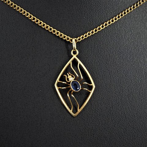 A 14k gold necklace with a spider shaped pendant set with a sapphire and pearl