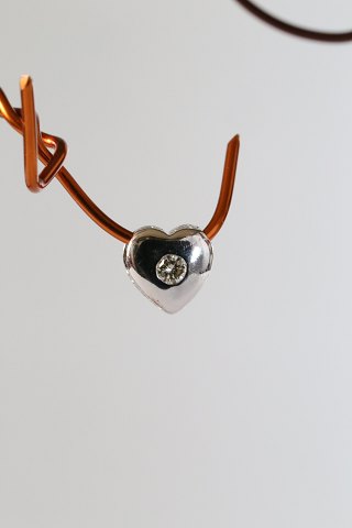 Small heart-shaped pendant for necklace, in 14 carat white gold, with a 
brilliant. Stamped 585