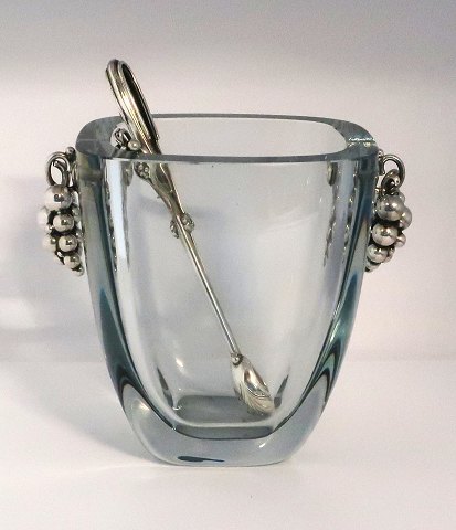 Dansk Guldsmede Haandværk, (DGH). Holmegaard isspand med sterling håndtag i form 
af en drueklase. Højde 15,5 cm. Bredde 13 cm. Medfølger tilhørende istang i 
sterling sølv.