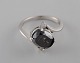 Large cocktail ring in 14 carat white gold with oval facet cut black diamond of 
approx. 3.50 ct. flanked by two brilliant-cut diamonds. Mid 20th century.
