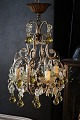 Dekorativ , gammel fransk lysekrone med klare glas prismer og glas kugler i en 
sart gul farve...