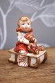 K&Co. præsenterer: Royal Copenhagen Pixie nisse i porcelæn , nr.764.Pige på kælk med lille bamse.