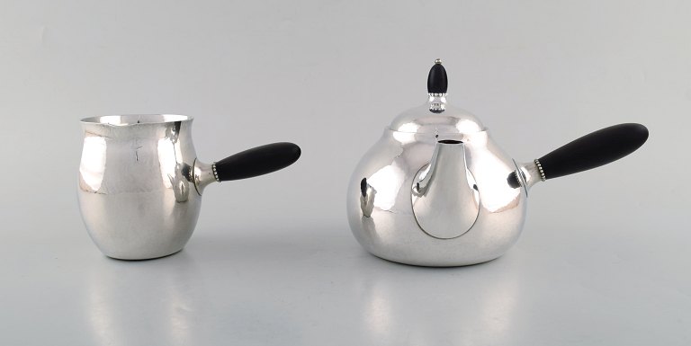 Georg Jensen art nouveau teapot and milk jug in sterling silver with handle and 
knob in ebony. Model Number 80A. Designed in 1915.

