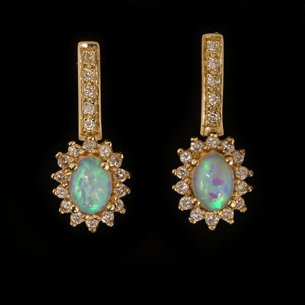 Pair of 14kt gold earrings each with an oval opal and 19 diamonds of ca. 
0,015ct. H: 24mm. W: 10mm