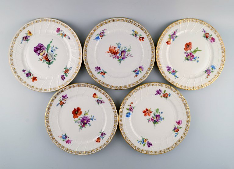 KPM, Berlin. Five antique dinner plates in curved porcelain with hand-painted 
flowers and gold decoration. Late 19th century.
