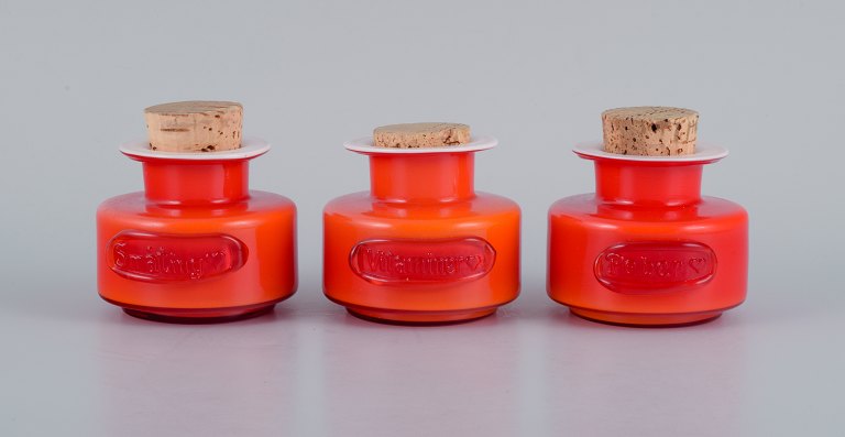 Michael Bang for Holmegaard. 
Tre krydderi-krukker - "Vitaminer", ”småting” og "peber". i orange og hvidt 
kunstglas.