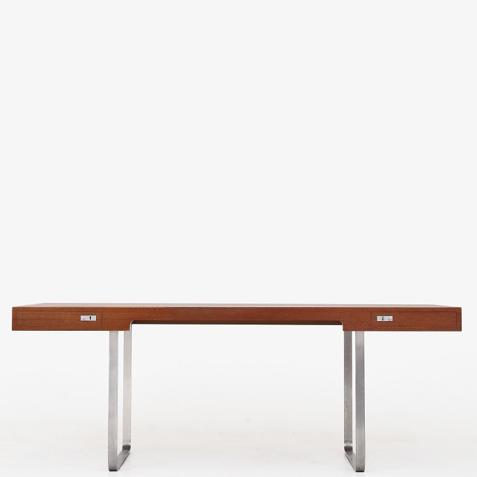 Hans J. Wegner / Johannes Hansen
JH 810 - Fritstående skrivebord med kassetteformet top i mahogni. Front med to 
skuffer, bøjlestel og greb af matforkromet stål. Formgivet i 1970.
1 stk. på lager
Pæn, brugt stand
