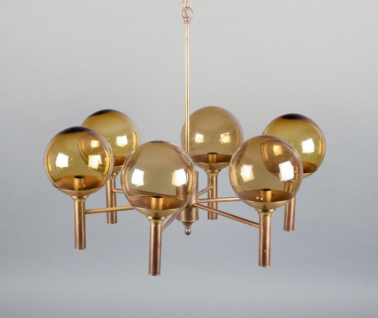 Sv. Mejlstrøm, dansk designer. Lysekrone af messing, seks arme med kuppelformede 
skærme af ravfarvet glas.