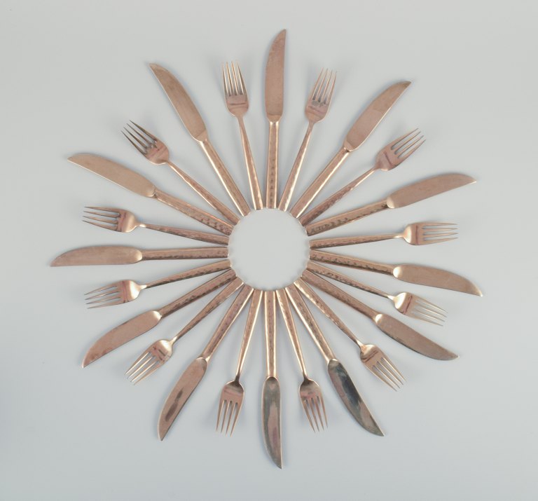 Scandinavian designer. Twelve-person dinner service consisting of twelve dinner 
knives and twelve dinner forks in handcrafted hammered brass. High-quality 
craftsmanship.